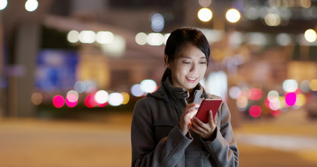 Woman look at the cellphone and searching for location in the the street at night