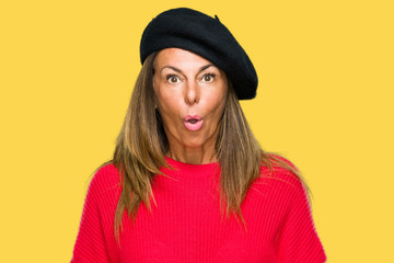 Middle age adult woman wearing fashion beret over isolated background afraid and shocked with surprise expression, fear and excited face.