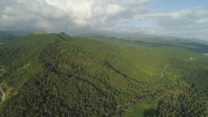 Aerial view of mountains covered rain forest, trees with clouds and sky. Luzon, Philippines. Slopes of mountains with evergreen vegetation. Mountainous tropical landscape. Cordillera region.
