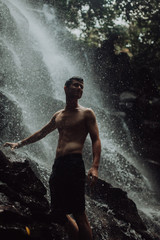 lean muscular Man look on waterfall in dark