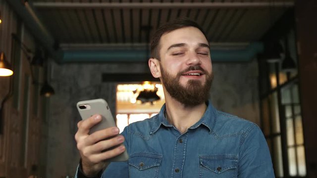 Face Id scanning . Portrait of a young man with a beard in a cafe. Blue shirt Man uses video call