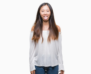 Obraz premium Young asian woman over isolated background sticking tongue out happy with funny expression. Emotion concept.