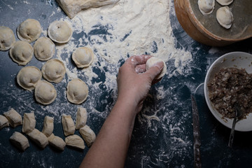 Female hand puts meat in the dough.