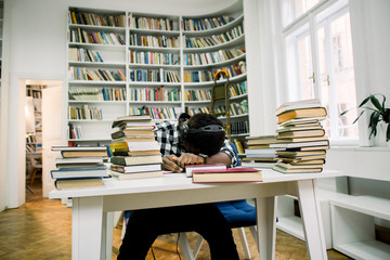 An African student sleeping at a desk in the library