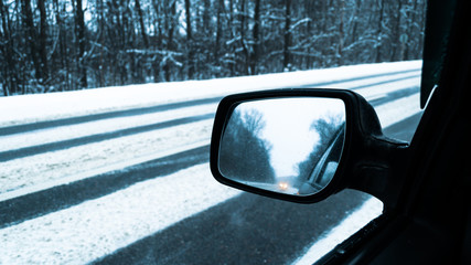 winter road from the car window. snow-covered track. view in the rear view mirror. Winter road, snow and ice.