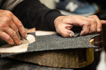 close-up of male shoemaker's hands cutting out shoe soles