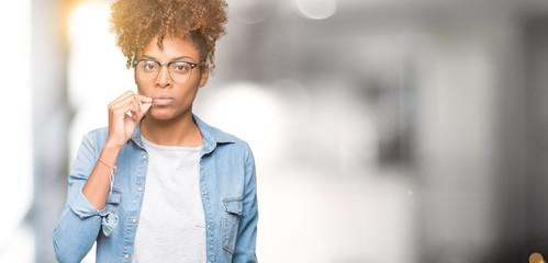 Beautiful young african american woman wearing glasses over isolated background mouth and lips shut as zip with fingers. Secret and silent, taboo talking - obrazy, fototapety, plakaty