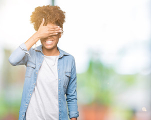 Beautiful young african american woman wearing glasses over isolated background smiling and laughing with hand on face covering eyes for surprise. Blind concept.