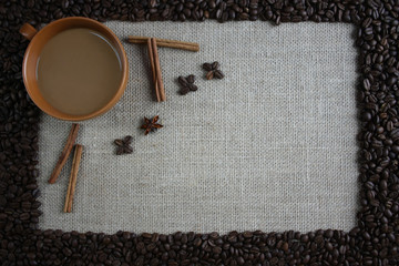 Filiżanka kawy otoczona cynamonem, anyżem i ziarnami kawy