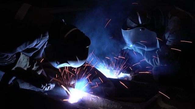 Welders welding metalwork in a factory