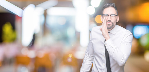 Fototapeta na wymiar Young handsome business man wearing glasses over isolated background hand on mouth telling secret rumor, whispering malicious talk conversation