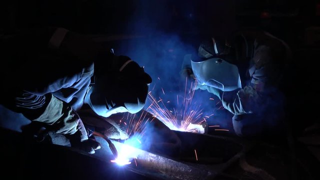 Welders welding metalwork in a factory