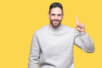 Young handsome man wearing sweatshirt over isolated background showing and pointing up with finger number one while smiling confident and happy.