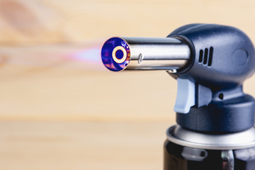 Blue flame with a manual gas burner on the wooden background.