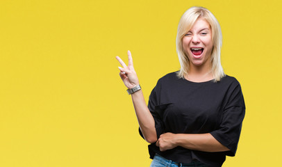 Young beautiful blonde woman over isolated background smiling with happy face winking at the camera doing victory sign. Number two.