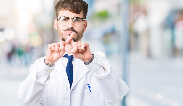 Young professional scientist man wearing white coat over isolated background Rejection expression crossing fingers doing negative sign