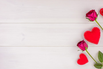 Romantic background with roses and hearts on a white wooden table. Top view, copy space.