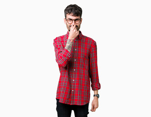 Young handsome man wearing glasses over isolated background smelling something stinky and...
