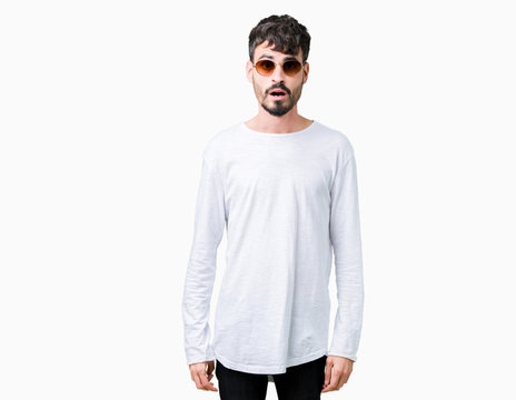 Young handsome man wearing sunglasses over isolated background afraid and shocked with surprise expression, fear and excited face.