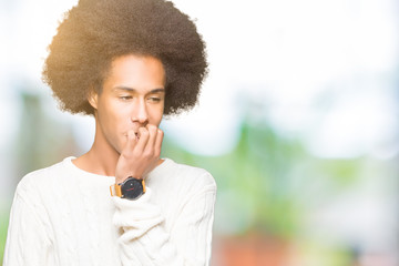 Fototapeta na wymiar Young african american man with afro hair wearing winter sweater looking stressed and nervous with hands on mouth biting nails. Anxiety problem.