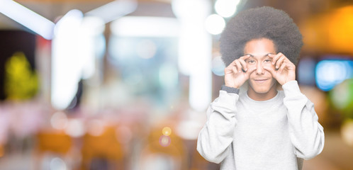 Young african american man with afro hair wearing sporty sweatshirt Trying to open eyes with fingers, sleepy and tired for morning fatigue