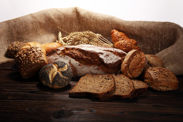 Different kinds of bread and bread rolls on board from above.