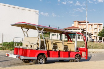 Red open sightseeing tourist minibus staying along sidewalk in Byala, Bulgaria.