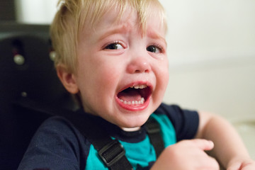 Portrait of boy crying while sitting on high chair at home