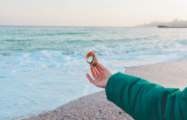Girl holding a sea shell on the beach in winter