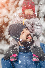 happy father and baby son having fun under sunny winter snow, holiday season.