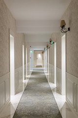 Photo of long bright and warm corridor inside hotel with many doors and lights