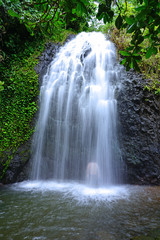 View of the silhouette of a man bathing under a cascading waterfall in Tahiti, French Polynesia © eqroy