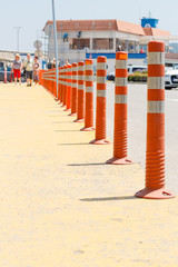 Lot of striped orange reflictive traffic bollards placed in row for safety and security between roads and pedestrian zone. City scene in city Varna, Bulgaria.