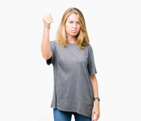 Beautiful young woman wearing oversize casual t-shirt over isolated background angry and mad raising fist frustrated and furious while shouting with anger. Rage and aggressive concept.