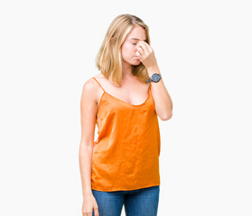 Beautiful young woman wearing orange shirt over isolated background tired rubbing nose and eyes feeling fatigue and headache. Stress and frustration concept.