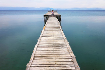 Naklejka premium woman sits on the pier, Corfu Greece
