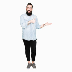 Young hipster man with long hair and beard wearing glasses Showing palm hand and doing ok gesture with thumbs up, smiling happy and cheerful