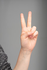 Victory sign made with one hand on a gray background
