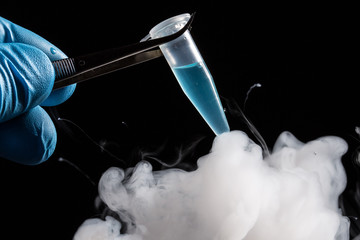 A scientist or lab personal freezes a tube filled with a light blue liquid in it