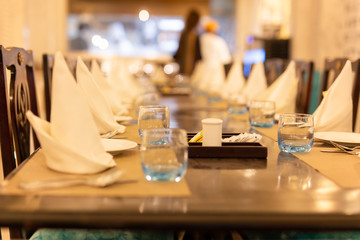 Selected focus of empty glass of water on dinner table with napkin.