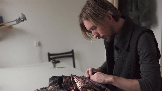Young male tailor working in furrier workshop
