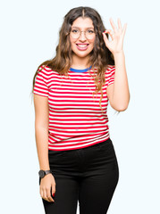 Obraz na płótnie Canvas Young beautiful woman wearing glasses smiling positive doing ok sign with hand and fingers. Successful expression.