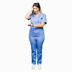 Young adult doctor woman wearing medical uniform Looking at the watch time worried, afraid of...