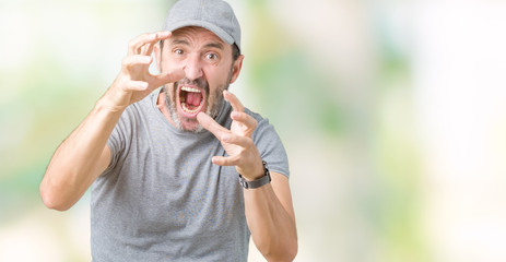 Handsome middle age hoary senior man wearing sport cap over isolated background Shouting frustrated with rage, hands trying to strangle, yelling mad