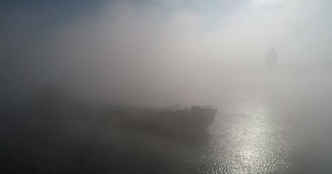 A huge barge on the river Dnipro in the morning fog with a visible silhouette of the buildings and city in the background (shot from the air) in 4K 7