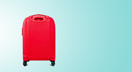 A red travel suitcase on wheels, isolated on a green pastel background. Travel concept, packing up before departure. Preparing for travel, going on vacation, break, rest.