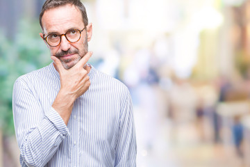 Obraz premium Middle age hoary senior man wearing glasses over isolated background looking confident at the camera with smile with crossed arms and hand raised on chin. Thinking positive.