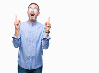 Middle age hoary senior man wearing glasses over isolated background amazed and surprised looking up and pointing with fingers and raised arms.