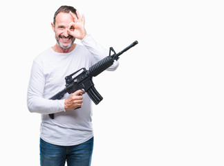 Middle age senior hoary criminal man holding gun weapon over isolated background with happy face smiling doing ok sign with hand on eye looking through fingers