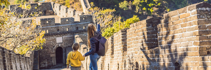 Fototapeta na wymiar Happy cheerful joyful tourists mom and son at Great Wall of China having fun on travel smiling laughing and dancing during vacation trip in Asia. Chinese destination. Travel with children in China